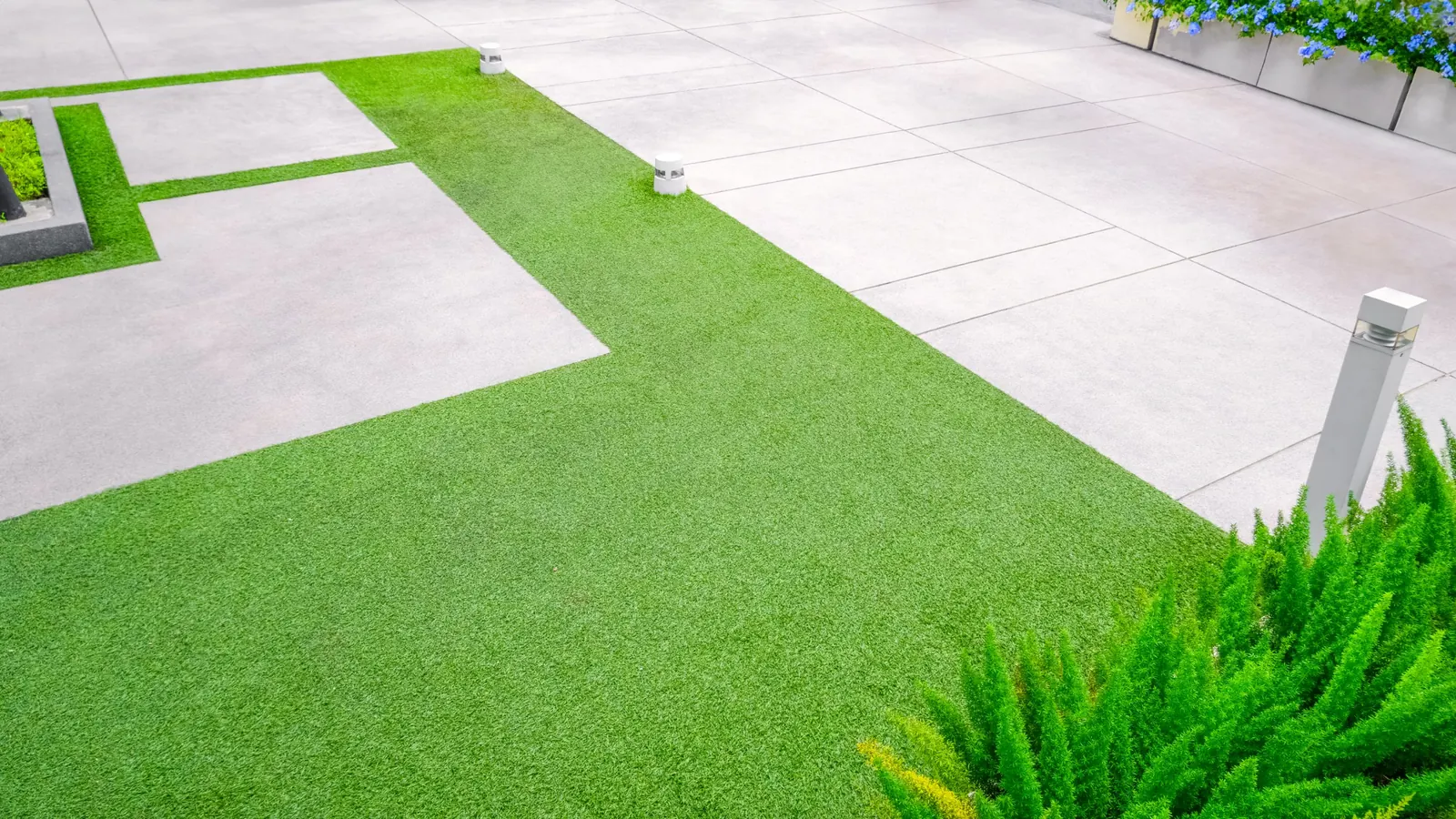 Artificial turf lawn with clean edges along a concrete paver patio and low path lights
