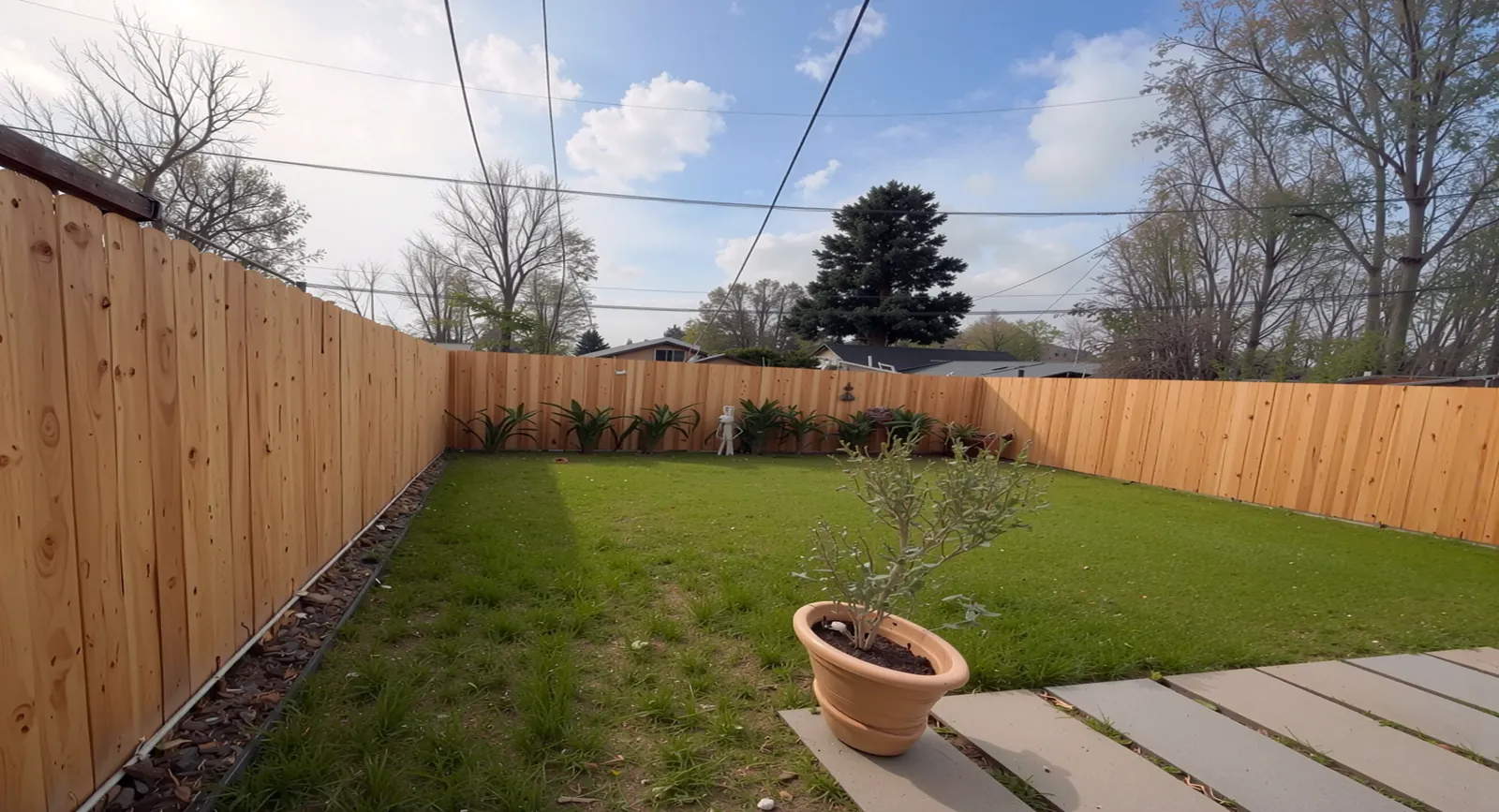 Wooden fence enclosing a backyard lawn with a paver patio in Houston, TX