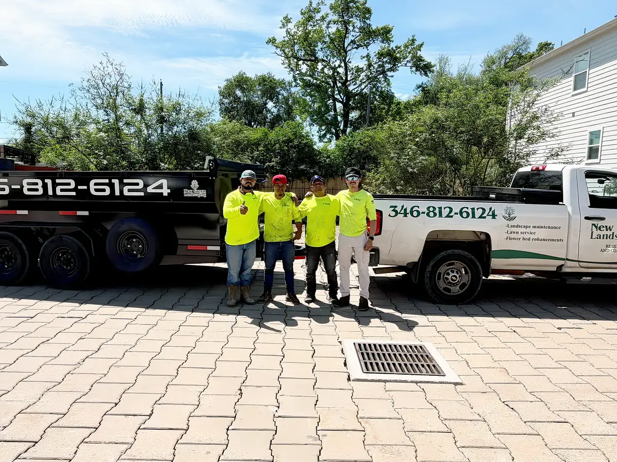 New Green Landscaping crew in high-visibility shirts standing between the company work truck and dump trailer in Houston, TX